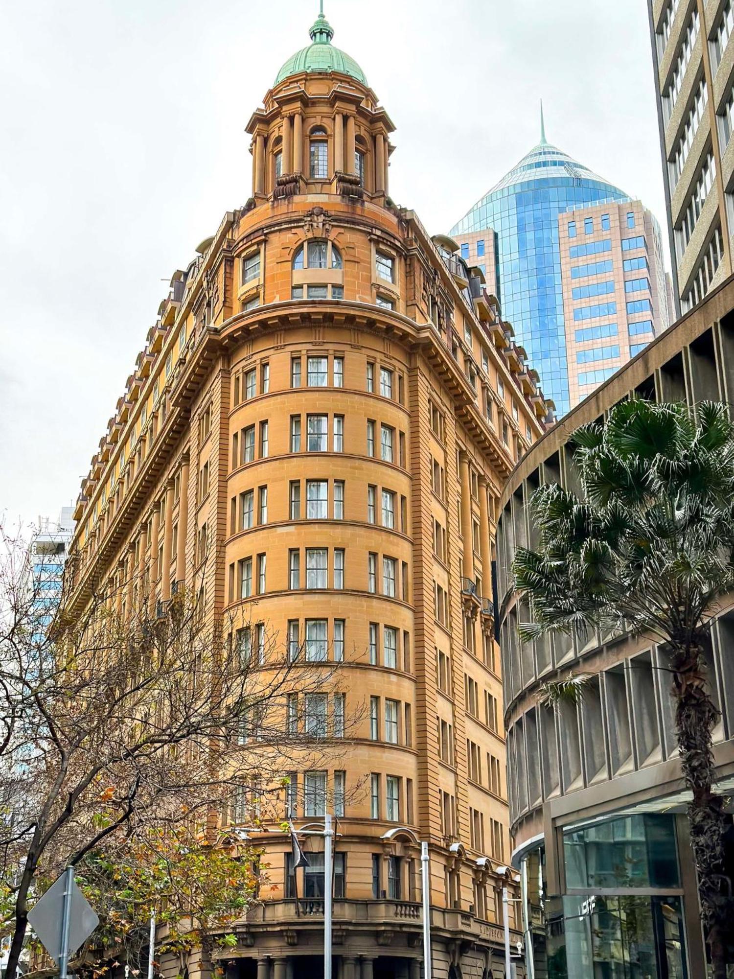 Radisson Blu Plaza Hotel Sydney Zewnętrze zdjęcie The photo shows a distinctive architectural building with a rounded facade, featuring a tan-colored exterior and multiple windows. This building is likely situated in an urban environment, surrounded by modern skyscrapers, indicated by the glass and 