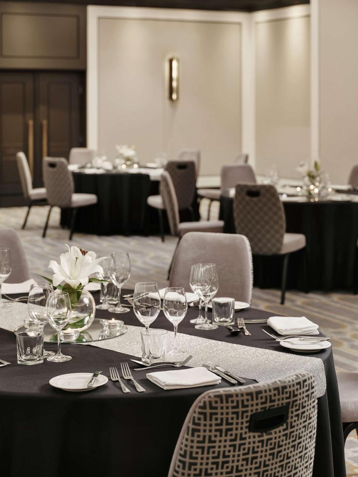 Radisson Blu Plaza Hotel Sydney Zewnętrze zdjęcie The photo shows a banquet or dining setup in a well-decorated room. In the foreground, there is a long table covered with a black tablecloth that features a silver runner. The table is set with various glassware, including wine glasses, water glasses